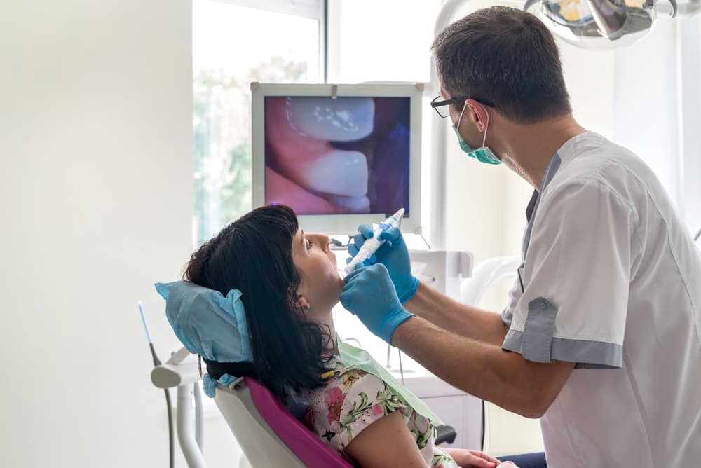 Dentist using an intraoral camera for a detailed examination of a patient's teeth during a checkup.